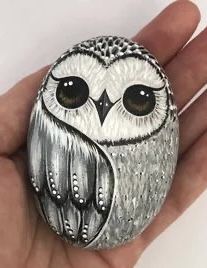 an owl painted on top of a rock in the palm of someone's hand