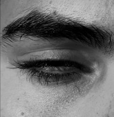 a close up view of the eye of a man with long black hair on his forehead