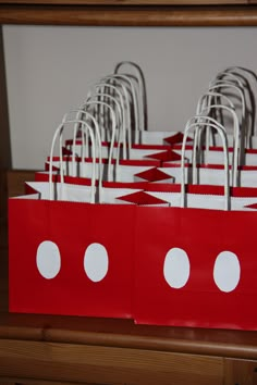 red paper bags with white polka dots are lined up in a row on a table