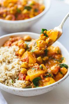 a spoon full of food with rice and spinach on the side next to another bowl