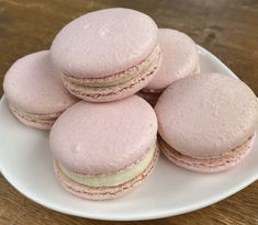 four pink macaroons sitting on top of a white plate