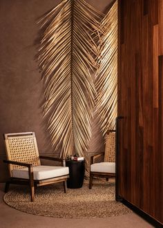 two chairs and a table in front of a wall with a palm leaf design on it