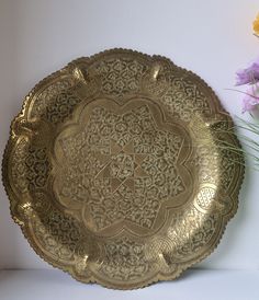 a gold plate sitting on top of a table next to flowers