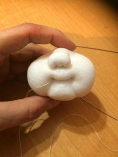 a person is holding something white on top of a wooden table and threading it together