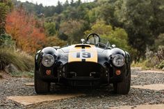 an old race car is parked on the gravel