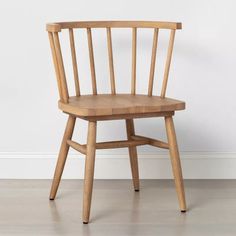 a wooden chair sitting on top of a hard wood floor next to a white wall