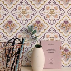 a white vase sitting on top of a table next to a wallpapered wall