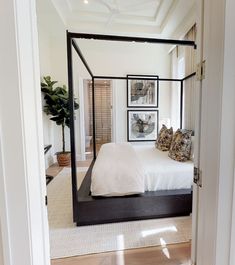 a bedroom with a four poster bed and pictures on the wall