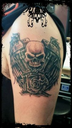 a skull and motorcycle engine tattoo on the back of a man's upper arm