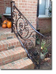 a wrought iron stair rail in front of a brick house with pumpkins on the steps