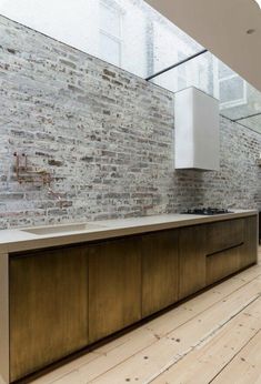 an empty kitchen with wooden floors and white brick walls