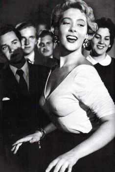 a black and white photo of marilyn monroe posing for the camera with other people behind her