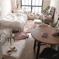 a bedroom with white bedding and pink rugs on the floor next to a wooden table