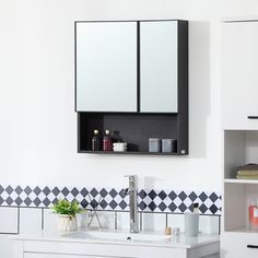 a white bathroom with black and white tiles on the wall, sink and mirror above it