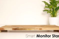 a wooden shelf sitting next to a potted plant on top of a white table