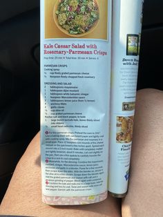 an open book on the back of a car seat with a salad in front of it