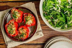 some food is sitting on a plate next to a bowl of greens and a salad