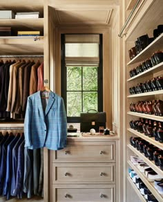 a closet filled with lots of different types of shoes and clothes hanging on wooden shelves