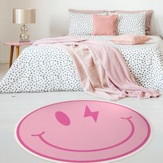 a pink smiley face rug on the floor next to a bed with polka dot sheets