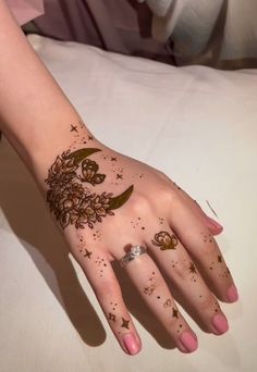 a woman's hand is decorated with hennap and stars on her left arm