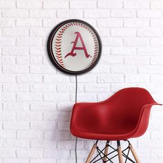 a red chair sitting in front of a white brick wall with a baseball on it