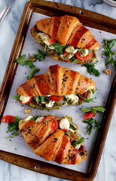 three sandwiches with meat and vegetables on a tray