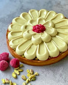 a cake with white frosting and raspberries next to it