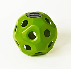 a green object with holes in it sitting on a white surface and facing the camera