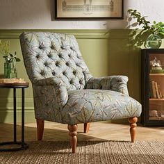 a blue chair sitting on top of a wooden floor next to a vase filled with flowers