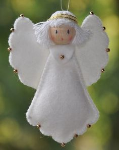 a white angel ornament hanging from a string with gold beading on it