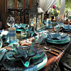 a dining room table set with blue dishes and place settings