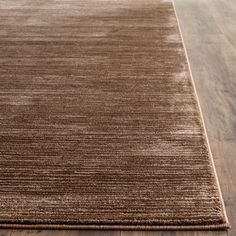 a brown area rug on top of a wooden floor with hard wood floors in the background