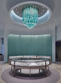 a circular glass table in the middle of a room with chandelier hanging from the ceiling