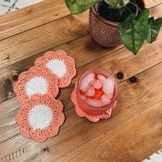 three crocheted coasters and a drink on a wooden table