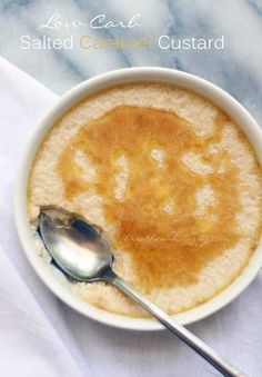 a white bowl filled with food next to a silver spoon on top of a table