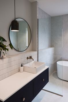 a bathroom with a sink, mirror and bathtub next to a plant in the corner