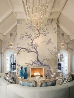 a living room filled with furniture and a fire place under a chandelier hanging from the ceiling