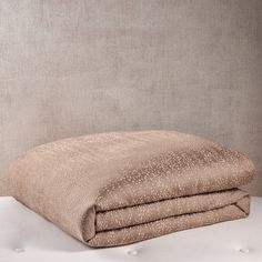 two pillows sitting on top of each other in front of a beige wall with white dots