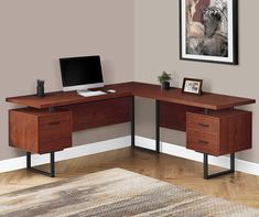 a corner desk with a computer on it in front of a gray wall and rug