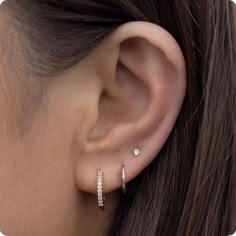 a woman's ear is shown with two small diamond hoops on the side