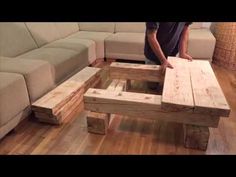 a man standing in front of a couch made out of wooden pallet boards on top of a hard wood floor