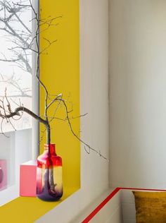 a yellow and red vase sitting on top of a window sill next to a tree