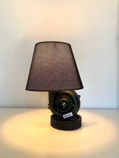 a lamp that is sitting on top of a table with a black shade over it