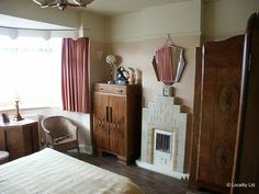 a bedroom with a bed, dresser, and chair in front of a window that has red drapes on the windowsill