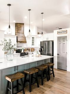 a kitchen with white counter tops and wooden stools next to an island in the middle