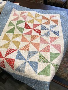 an old quilt is on the table next to a chair