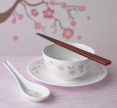 two chopsticks and a bowl on a pink table cloth with cherry blossoms in the background