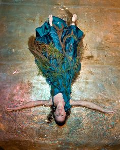 a woman laying on the ground in water with her arms spread out and head down