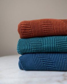 three knitted blankets stacked on top of each other