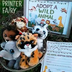 several stuffed animals are in a basket on the grass next to a sign that says adopt a wild animal